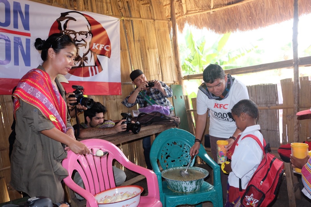 Hendra Yuniarto, General Manager Marketing KFC Indonesia turut membagikan bubur kacang hijau kepada murid-murid SD Negeri Kofi saat kunjungannya